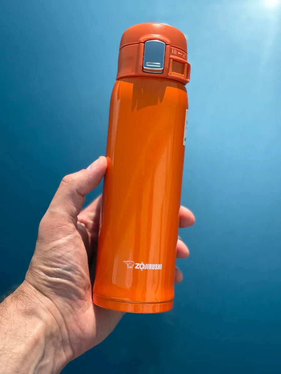 Zojirushi SM-SHE orange travel mug in hand, lightweight and ideal for commuting