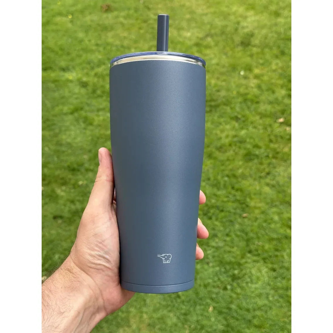 zojirushi dark blue straw tumbler in hand, background green grass